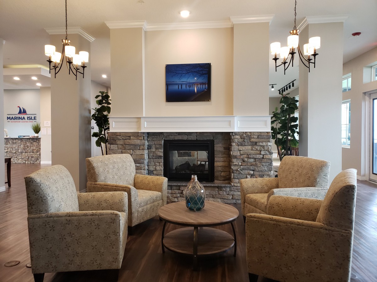 A cozy living room with a stone fireplace, surrounded by comfortable armchairs and elegant chandeliers.