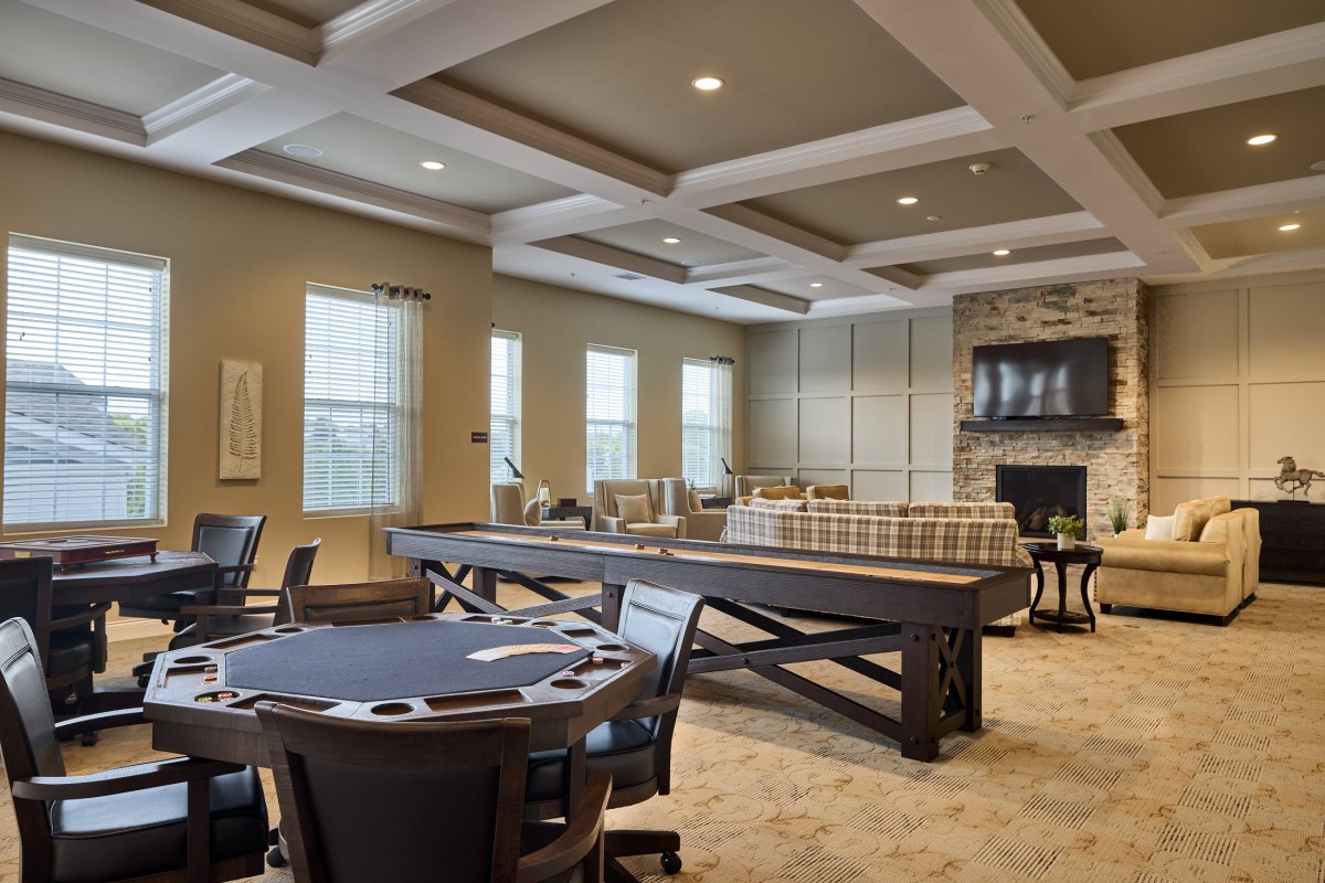 A modern game room with a pool table, poker table, and comfortable seating area.