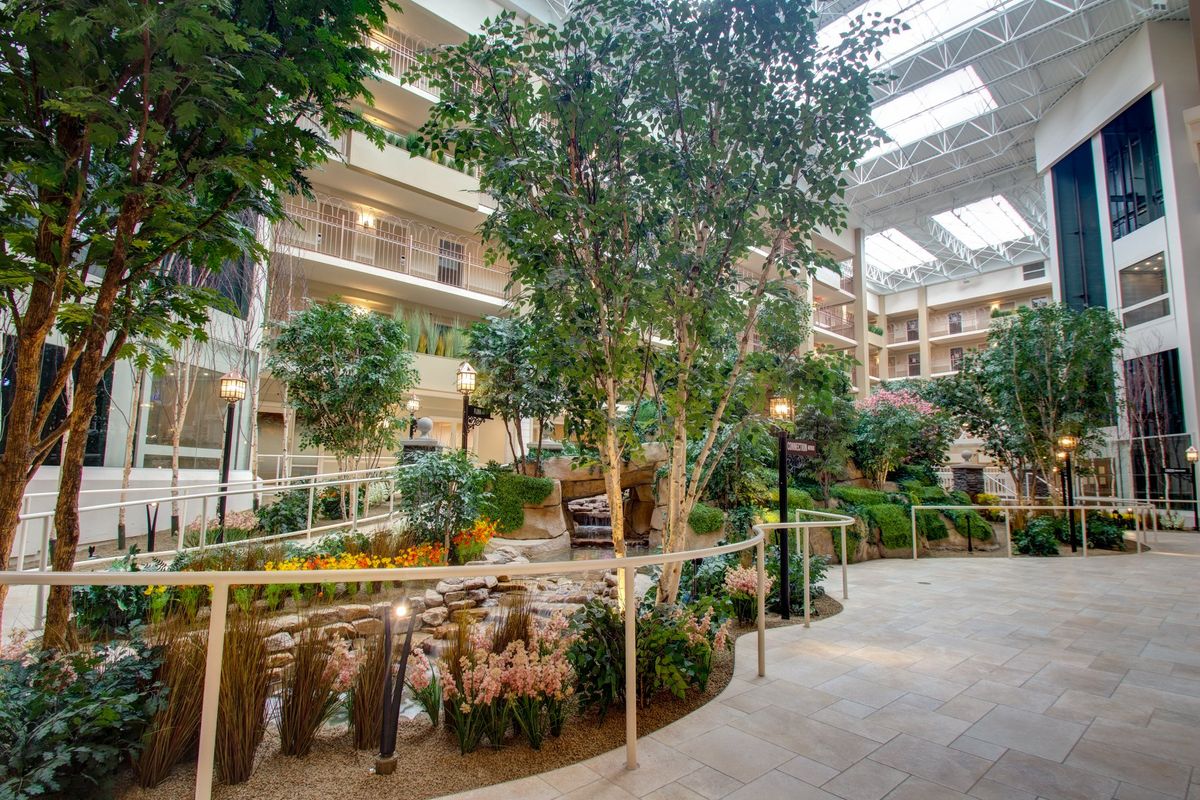 A spacious indoor atrium filled with lush greenery and a walking path under natural light.