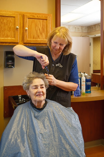 A hairdresser styles the hair of a senior woman, creating a moment of care and connection.