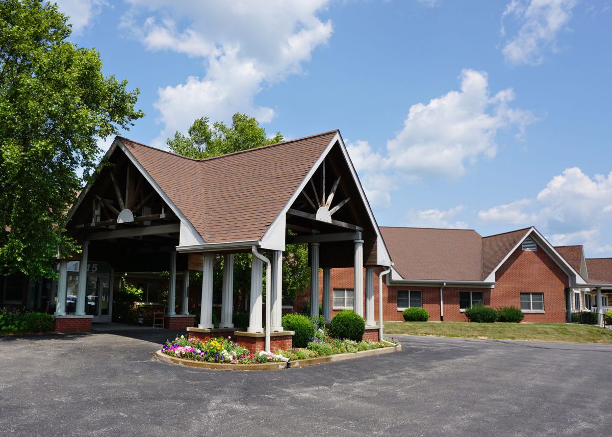 An entrance to a building with landscaped surroundings under a partly cloudy sky.