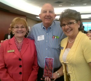 A group of three individuals celebrating an achievement at a public event.