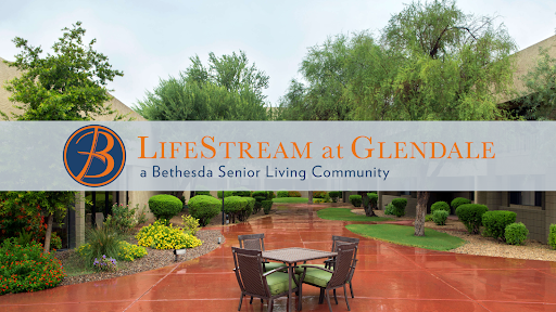 Entrance to LifeStream at Glen, a senior living community, featuring outdoor seating and lush landscaping.