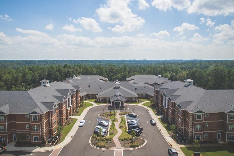 Aerial view of a suburban housing complex with well-maintained landscaping and parking areas.