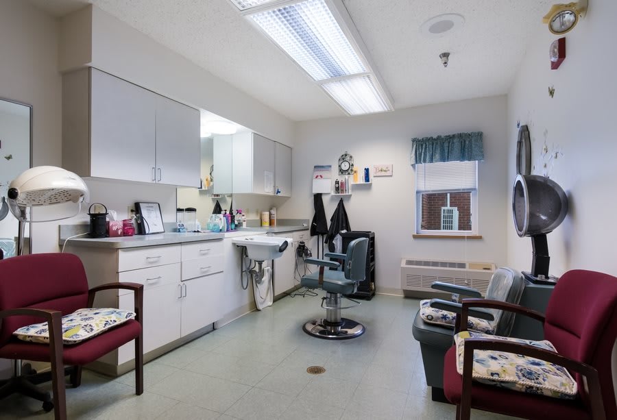 A well-lit hair salon with a barber chair, mirrors, and a waiting area.