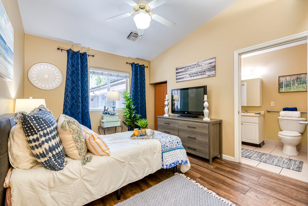 A modern bedroom featuring a comfortable bed, stylish decor, and a TV on a wooden dresser.