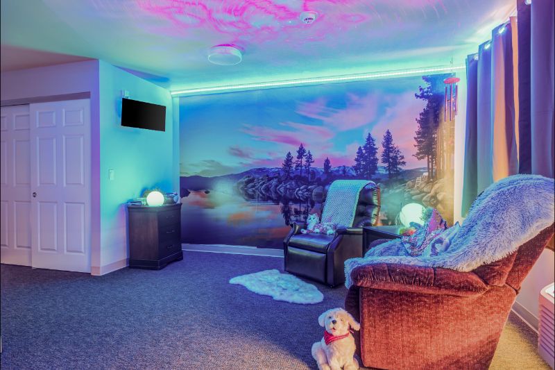 A cozy room with neon lights illuminating a scenic wall mural, featuring comfortable seating and decorative elements.