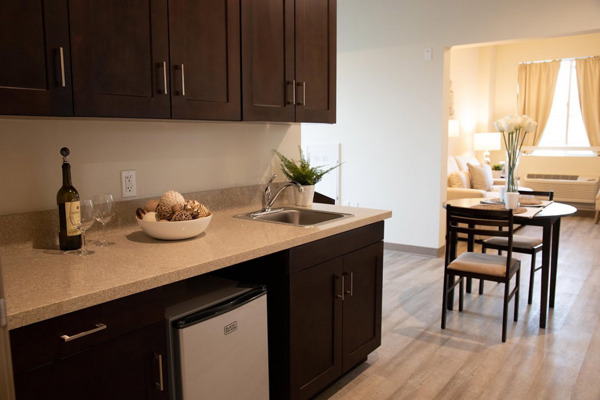 A modern kitchen setup with dark wood cabinets, a small fridge, and a sink on the countertop.