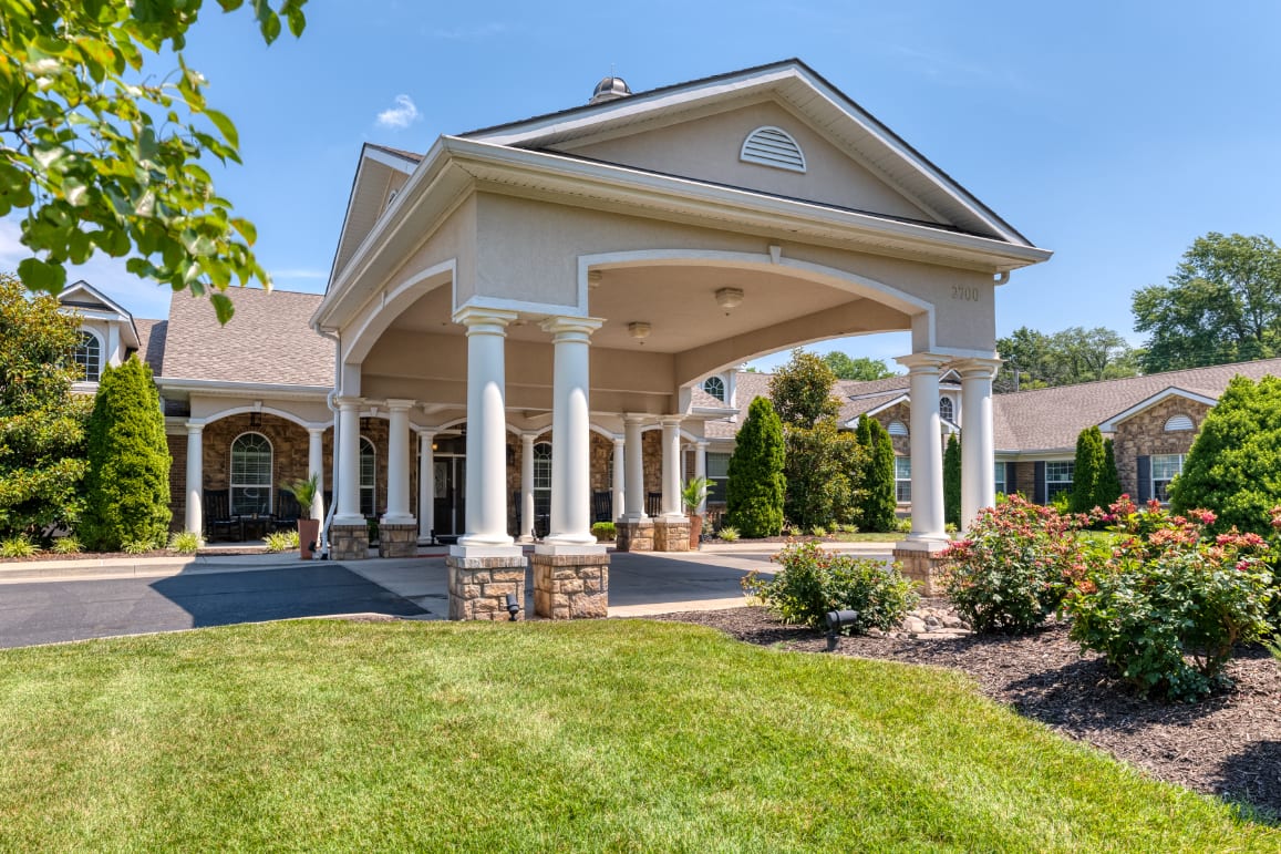Elegant building entrance with landscaped garden and columns.