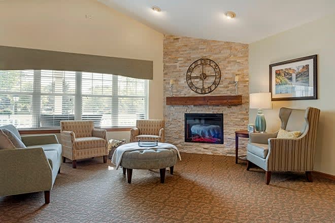A cozy living room with a stone fireplace, ample seating, and plenty of natural light.