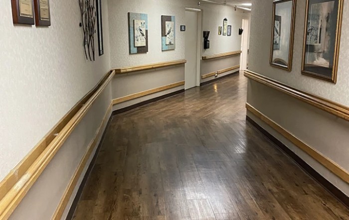 A long hallway with wooden flooring and artwork on the walls.