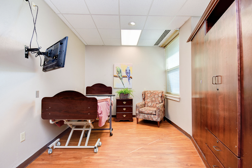 A well-lit patient room featuring a hospital bed, an armchair, and modern furnishings.