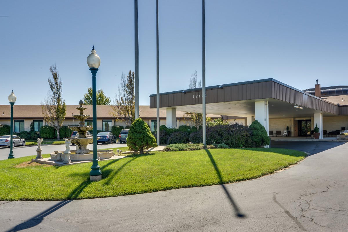 Entrance to a hotel with flagpoles and landscaped surroundings.