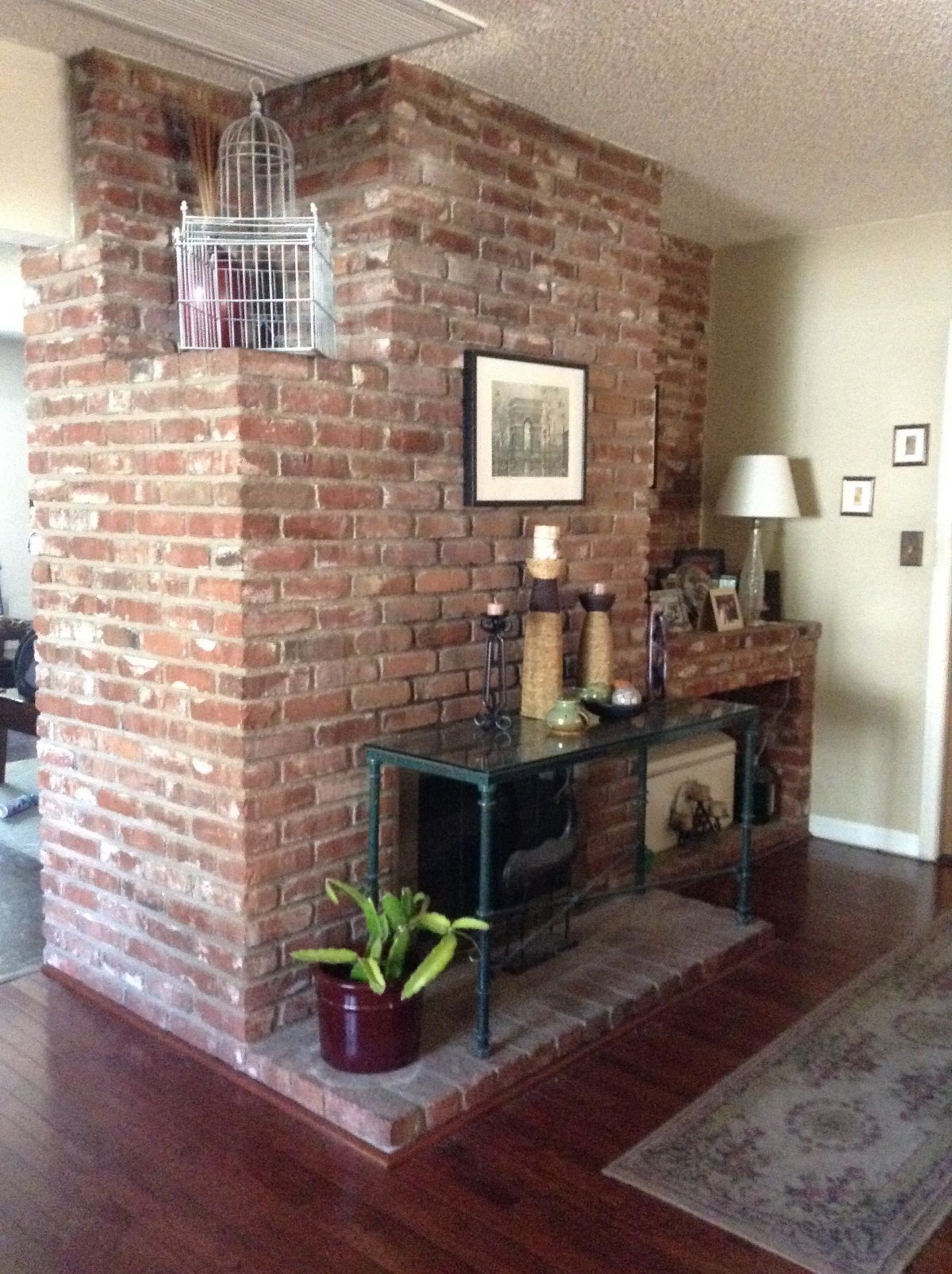 A cozy living room with an exposed brick wall, decorated with candles, a plant, and artwork.