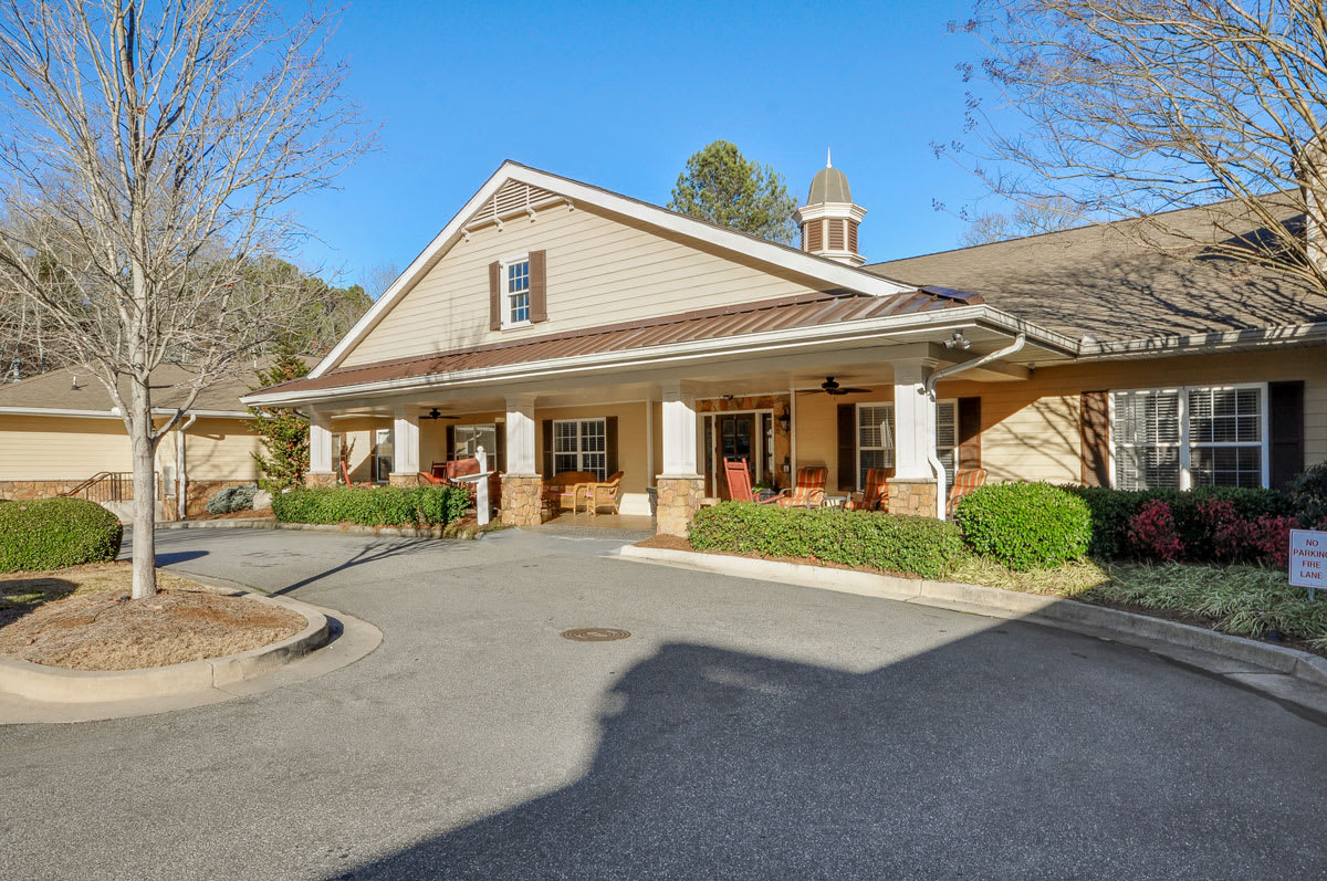 A large residential building with a porch, photographed during the daytime.