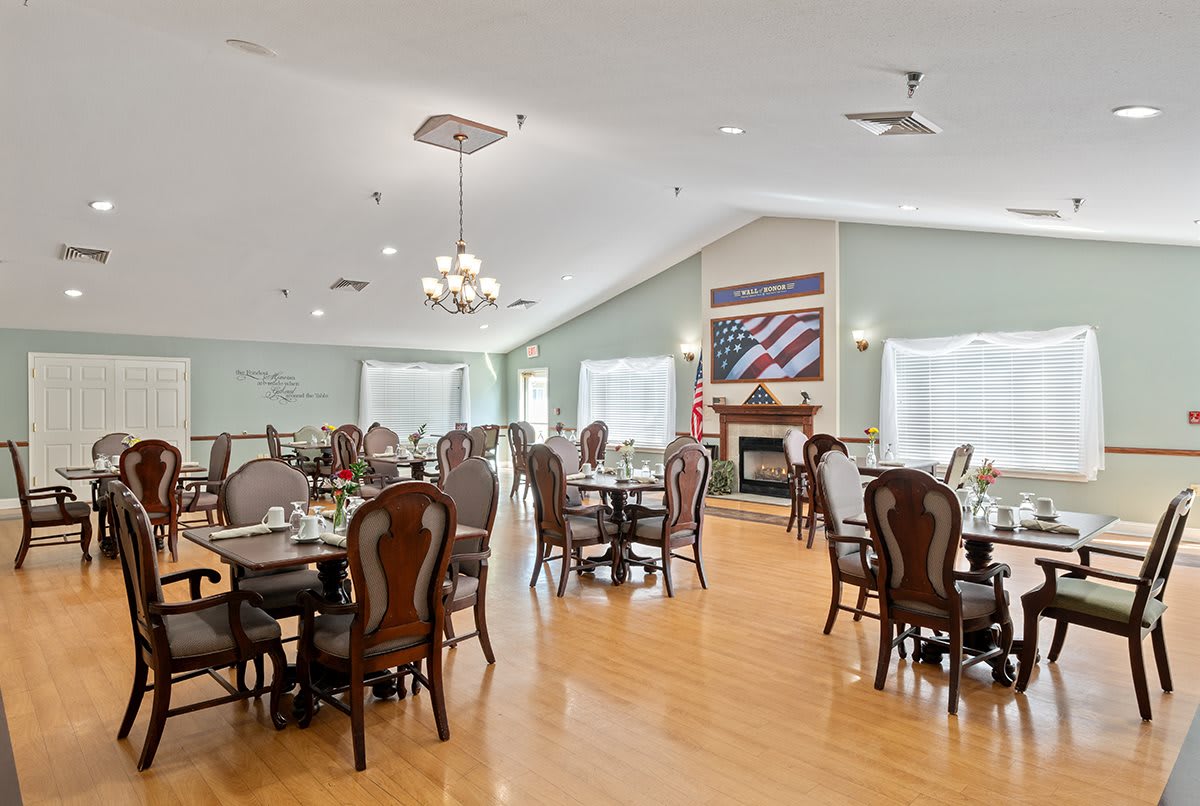 A spacious dining area with elegant tables and chairs, featuring a fireplace and flag-themed artwork.