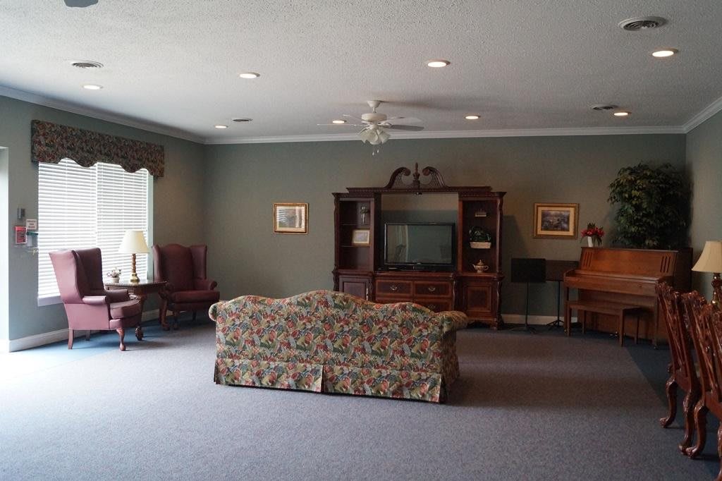 A spacious living room with a patterned sofa, television console, and classic furniture.
