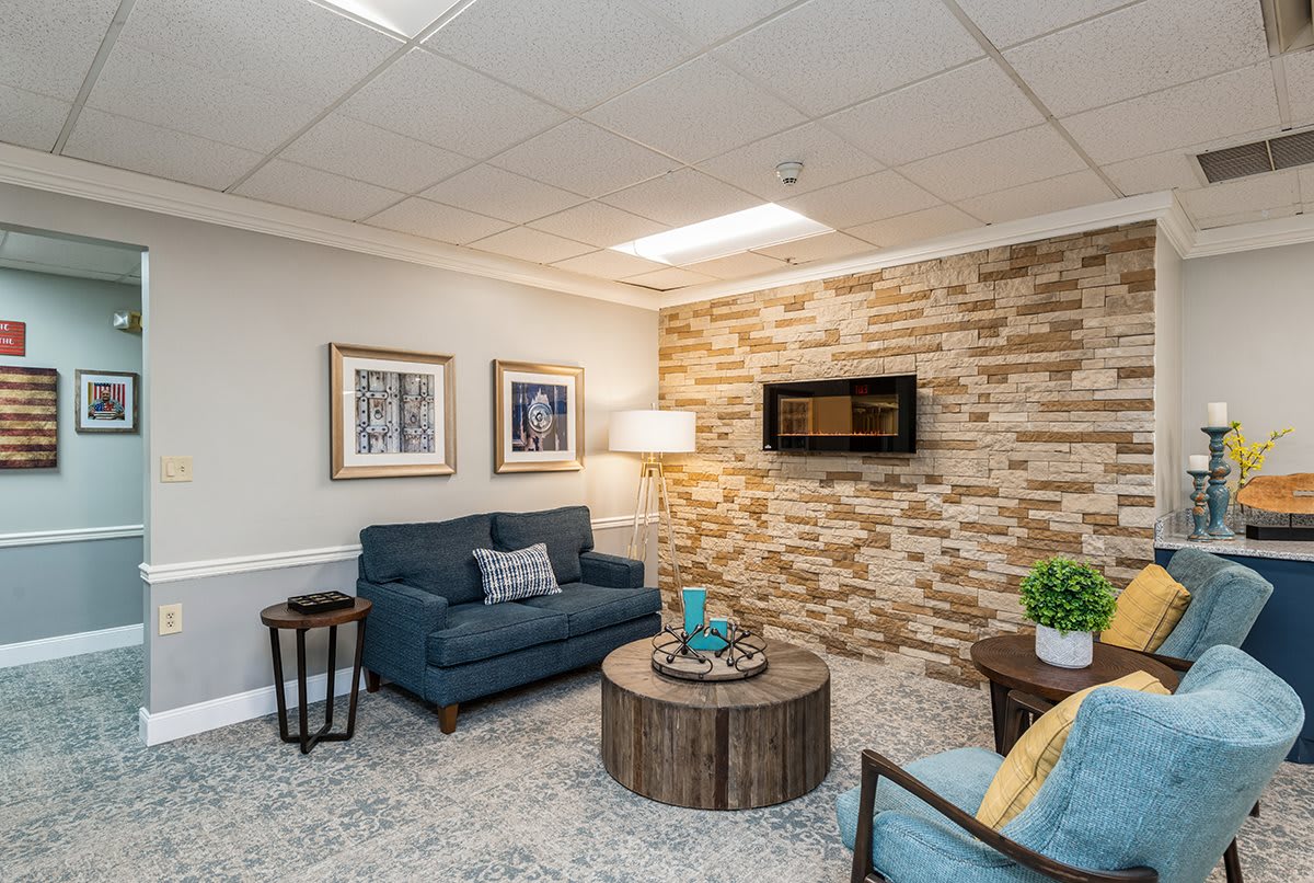 A cozy living room with a blue sofa, round coffee table, and wall art.