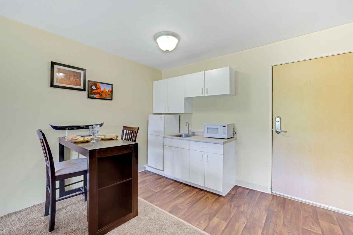 A cozy kitchenette with dining table, cabinets, and appliances.