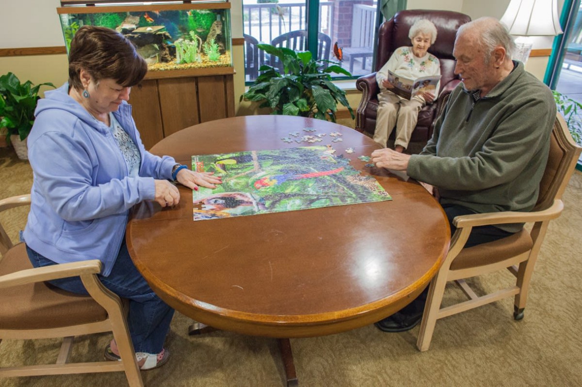 Seniors engaged in solving a puzzle at a community center.