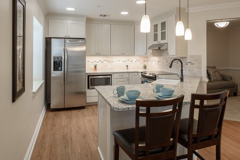 A modern kitchen featuring an island with seating, stainless steel appliances, and pendant lighting.