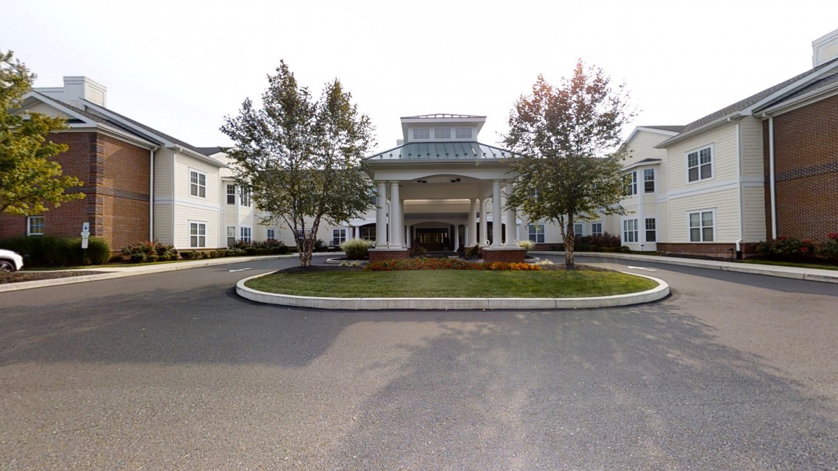 Front view of a building with landscaped entrance and surrounding trees.