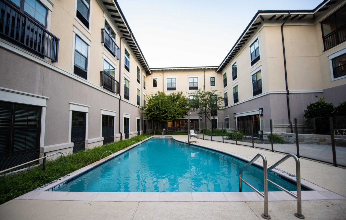 A modern apartment complex featuring a central outdoor swimming pool.