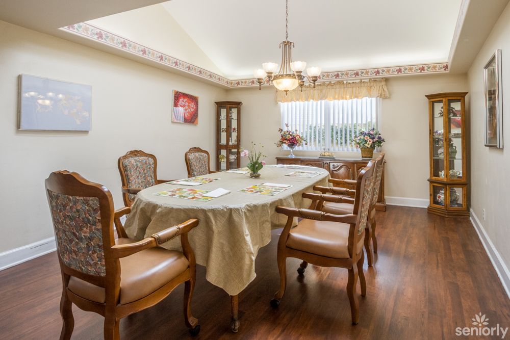 A classic dining room with a table and chairs set, adorned with a chandelier and decorated curtains.