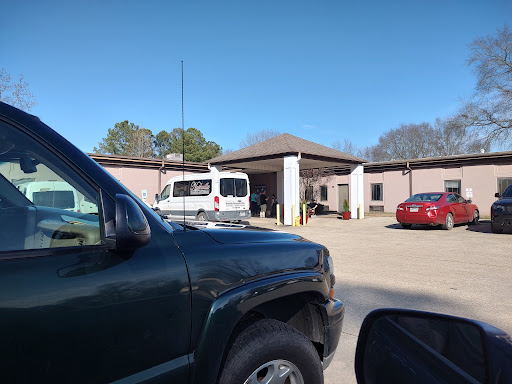 A view of a parking lot with various vehicles and a building in the background on a clear day.