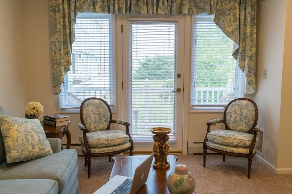 A cozy living room with elegant furniture and large windows overlooking a backyard.