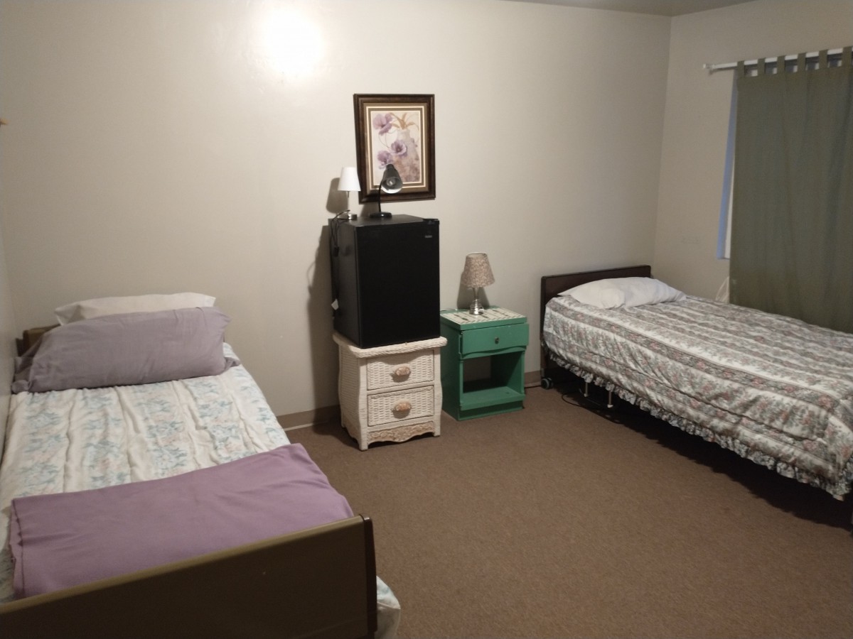 A simple bedroom with two beds, two nightstands, and a piece of artwork on the wall.