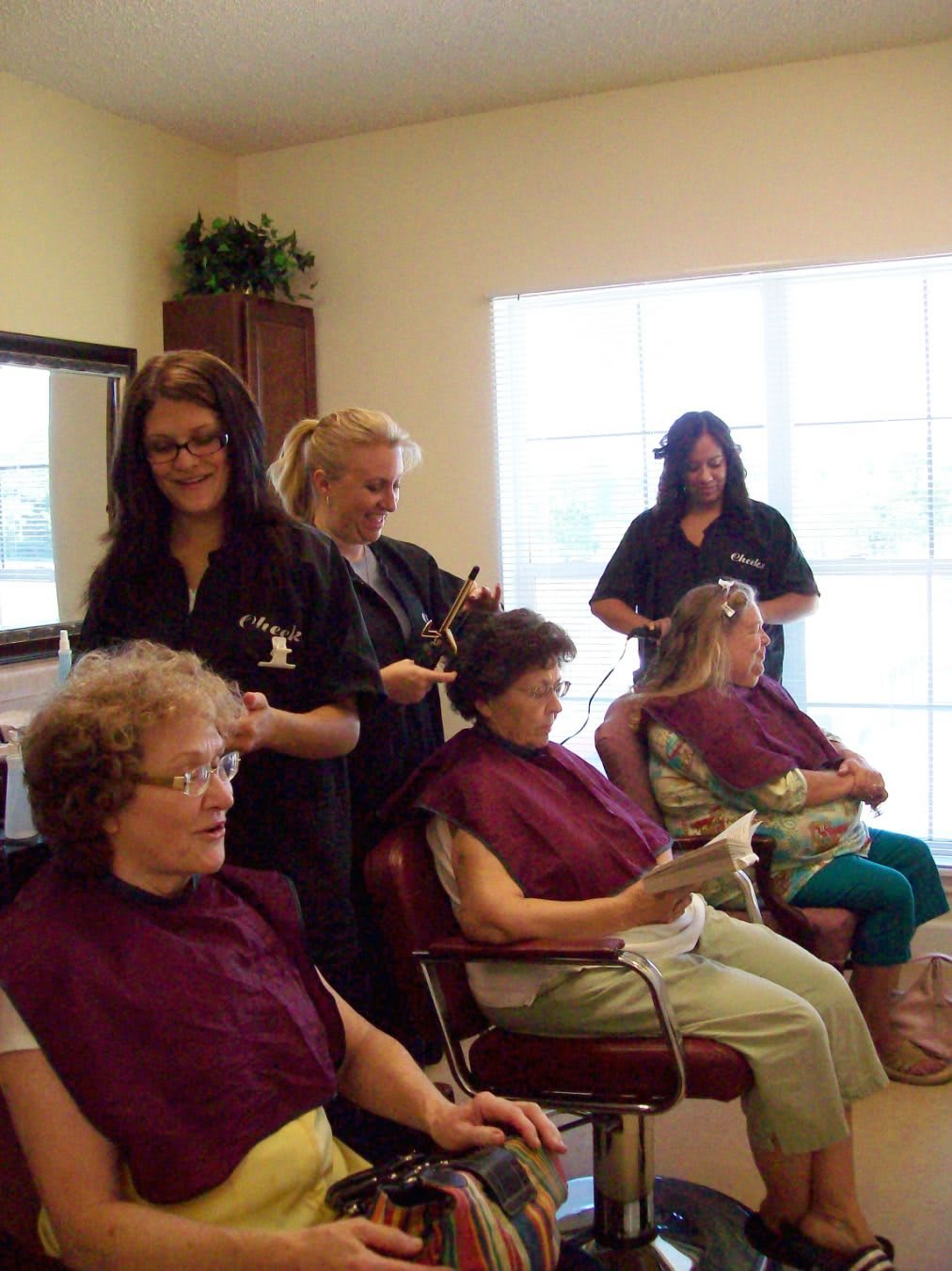 Hairstylists attending to elderly women in a salon.