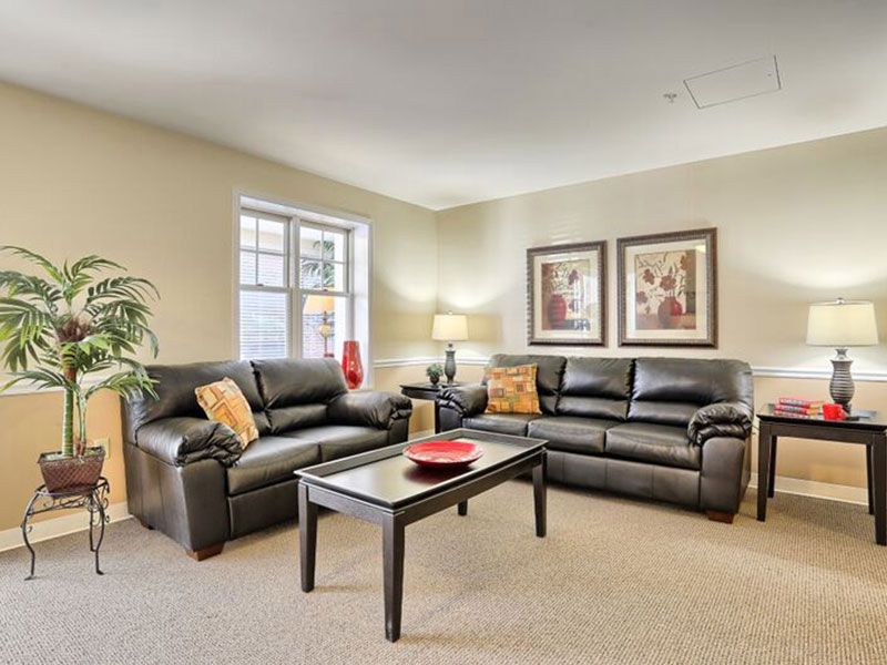 A cozy living room featuring black leather sofas and a central coffee table.