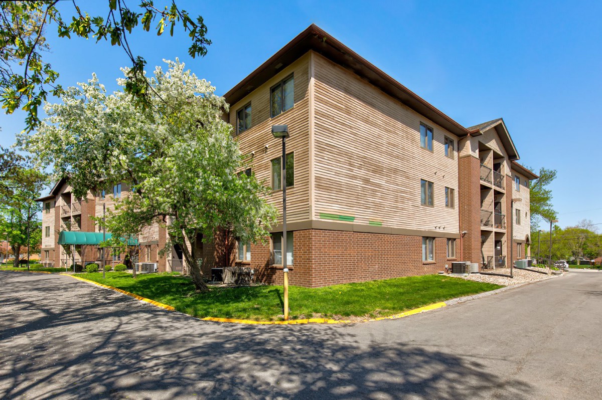 A residential apartment building with surrounding greenery on a sunny day.