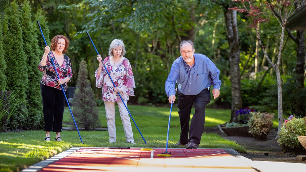 A group of seniors enjoying a game of shuffleboard in a lush garden setting.