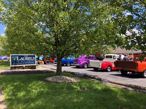 A lineup of vibrant vintage trucks parked near a sign, surrounded by lush greenery.