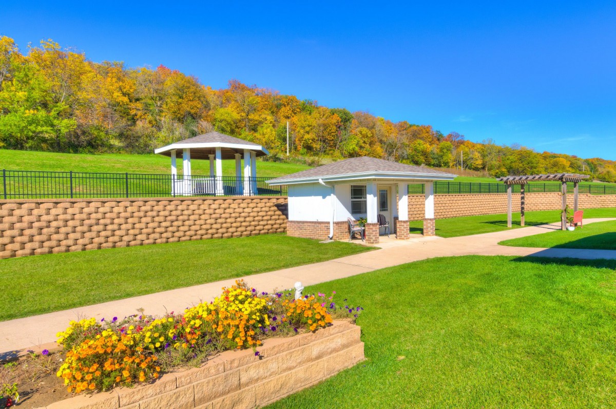 Beautiful park landscape with gazebos, greenery, and a pathway on a sunny autumn day.
