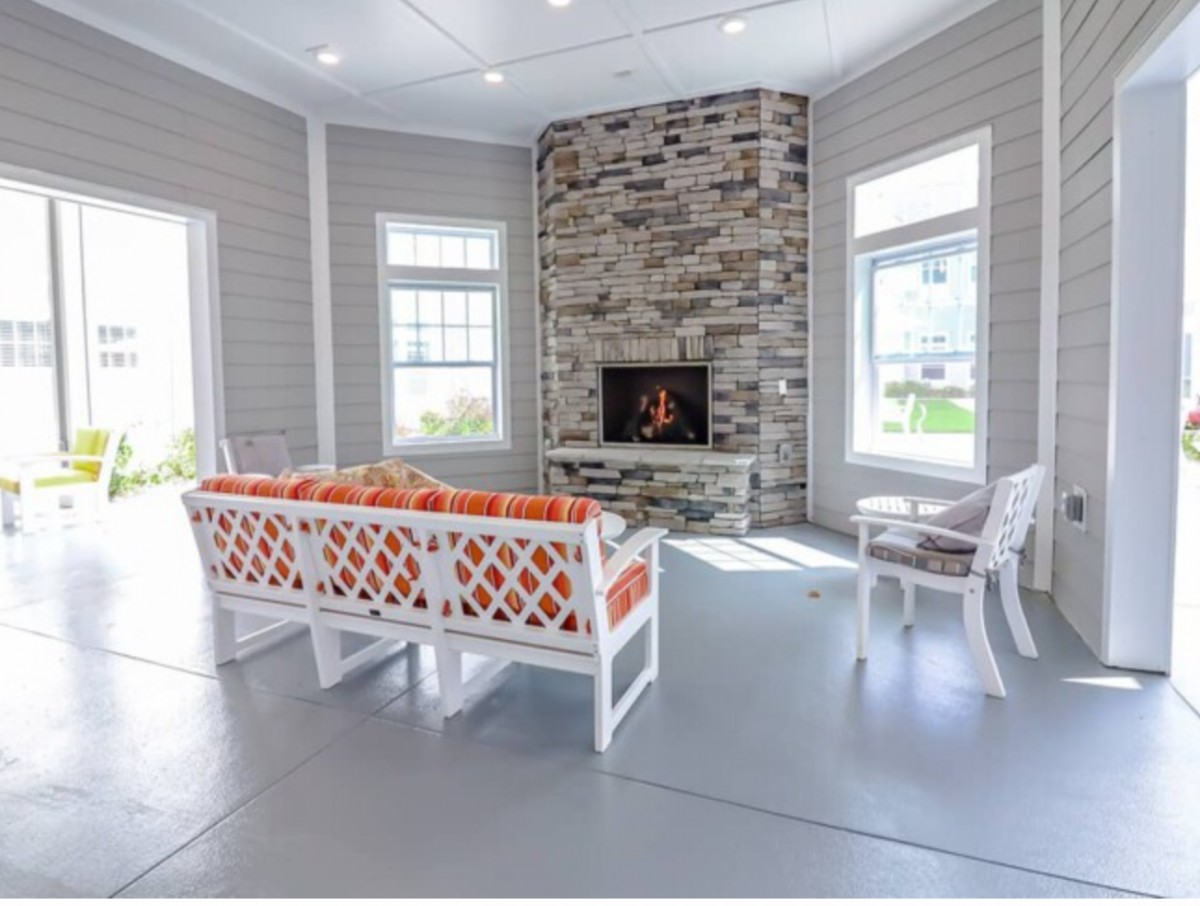A cozy living room with a stone fireplace and bright windows.