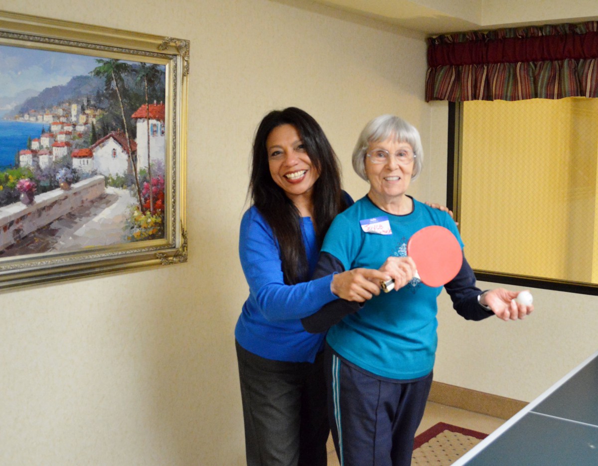 Two women playing table tennis indoors.