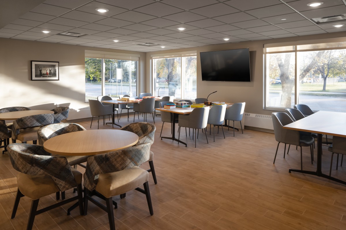 A modern dining area with tables, chairs, and a wall-mounted television.