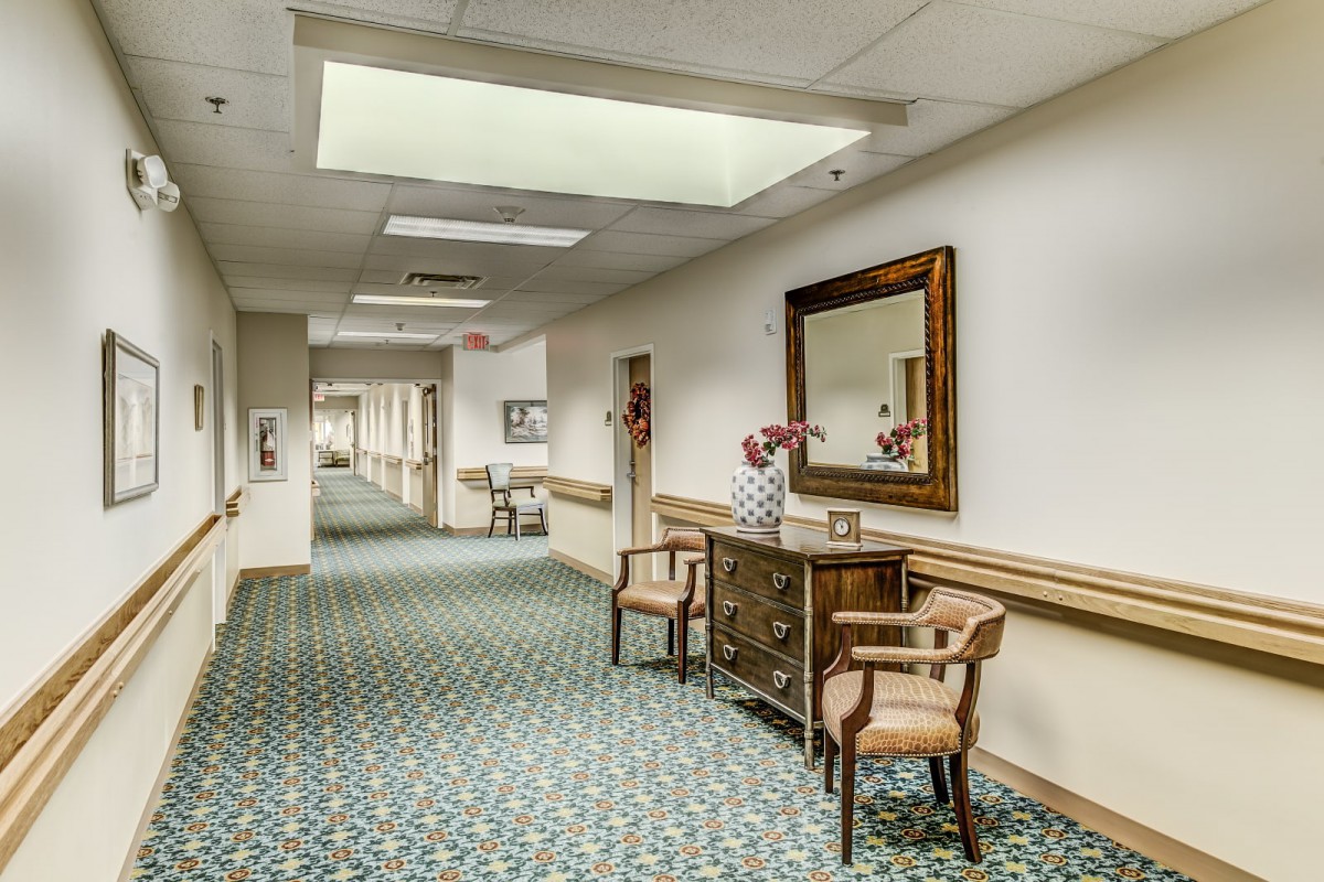 A quiet hallway with decorative furniture and a large mirror.