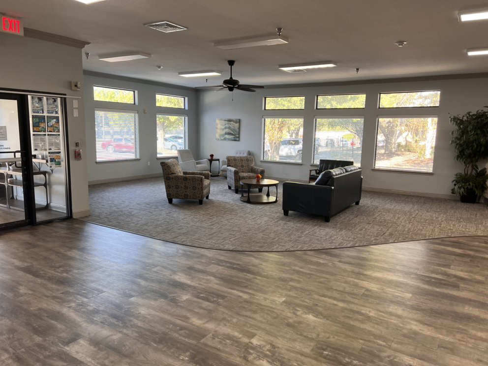 A modern living room with ample natural light, featuring comfortable seating and a neutral color palette.