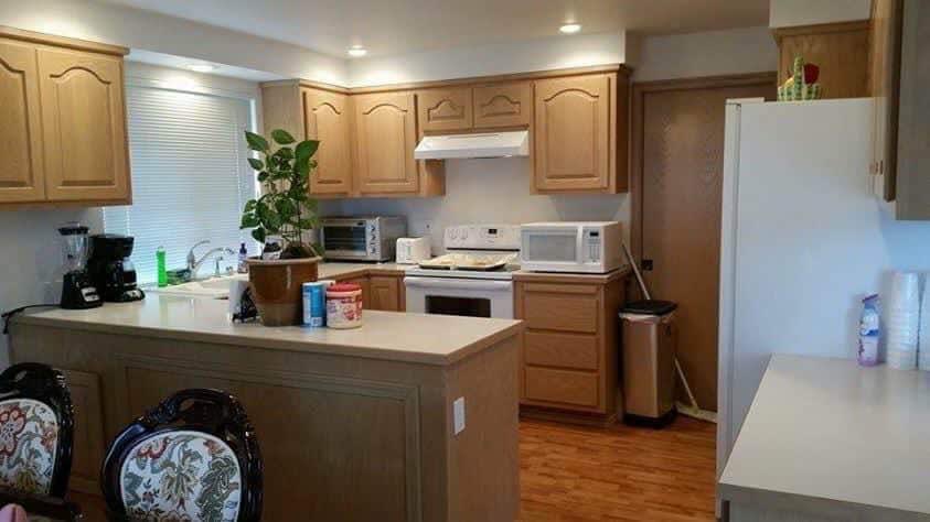 A cozy kitchen with wooden cabinets, appliances, and a small potted plant on the countertop.