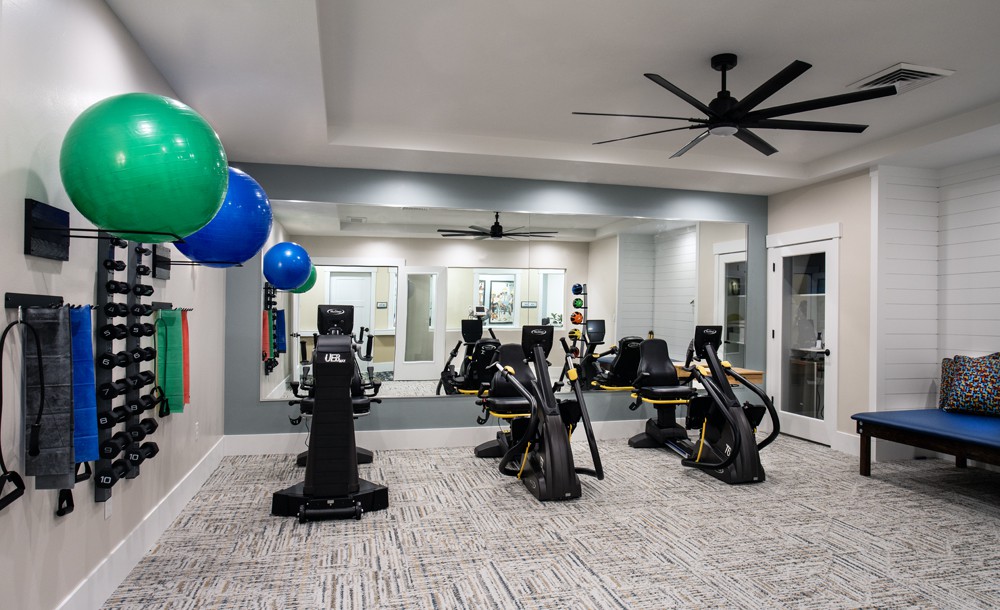 A modern gym with various cardio machines and decorative balloons.