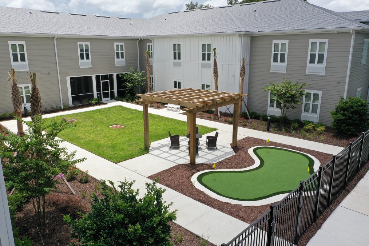 A well-maintained courtyard with a pergola and seating area surrounded by a manicured lawn and landscaping.