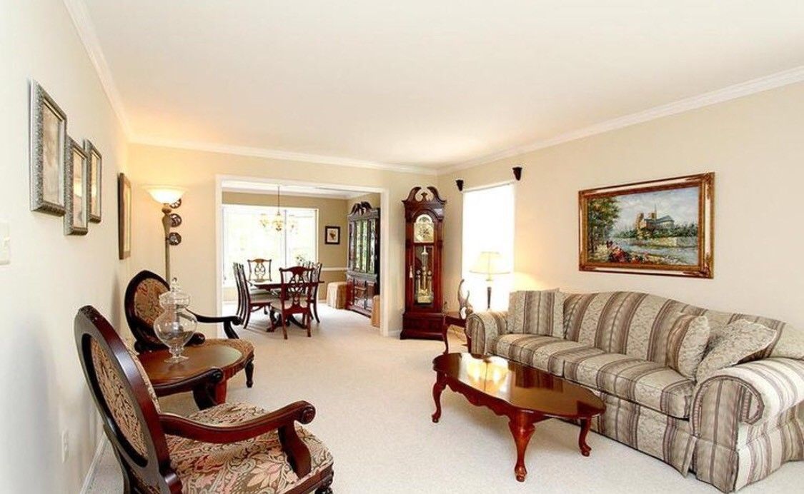 A traditional living room with a sofa, armchair, grandfather clock, and coffee table.