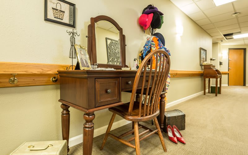 A vintage wooden vanity with a mirror and chair, adorned with decorative items.