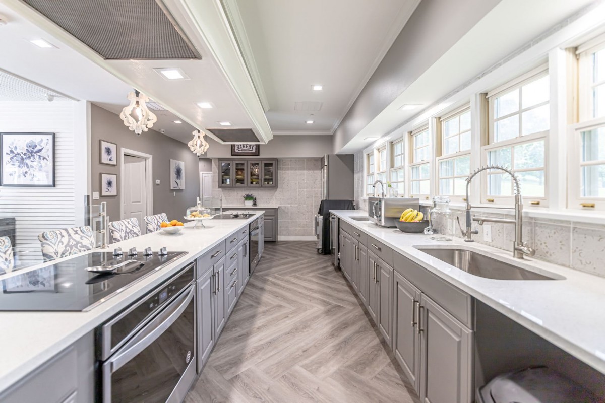 A modern kitchen with gray cabinets, ample countertops, and large windows providing bright natural light.
