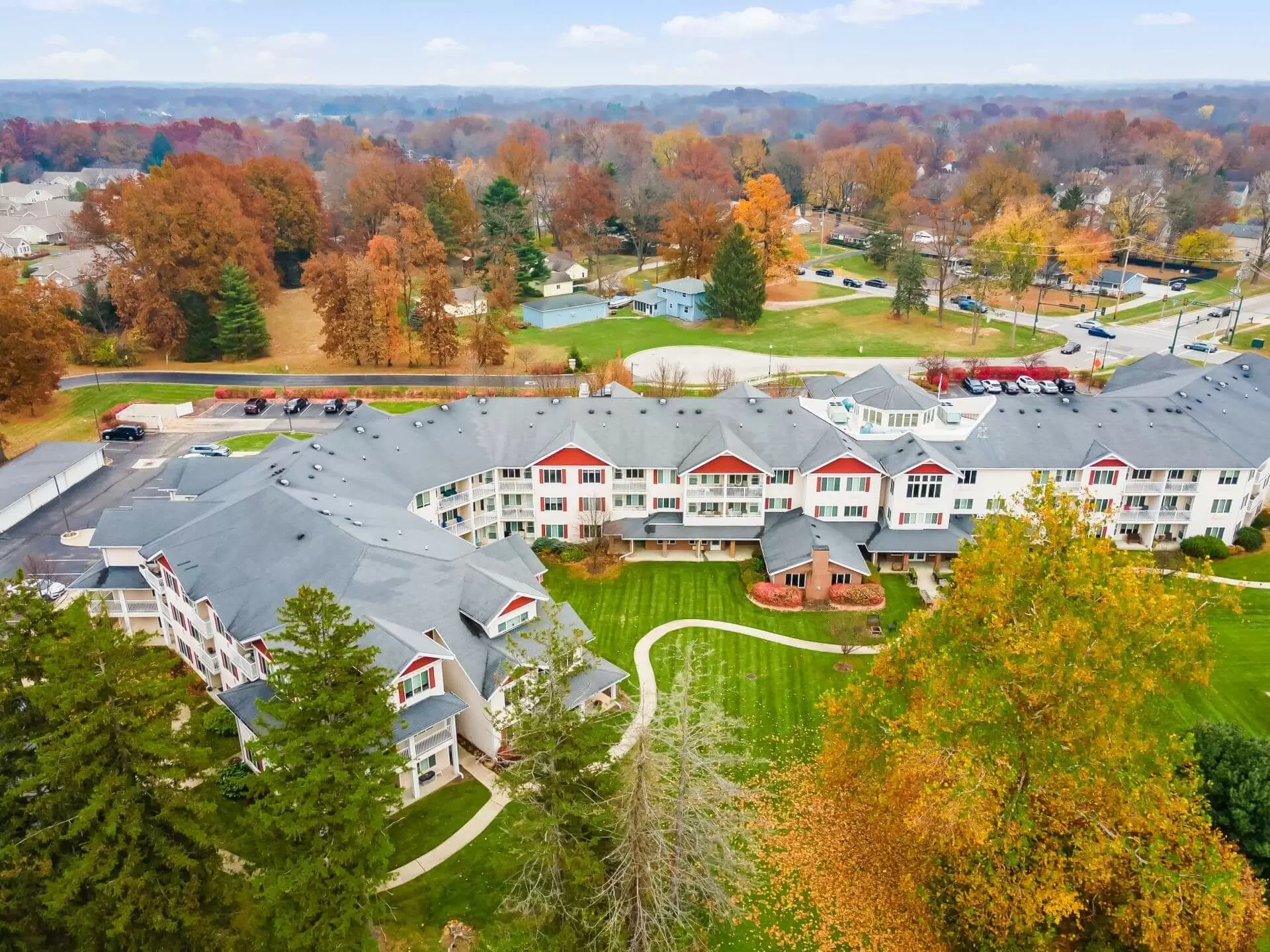Aerial view of a residential building surrounded by colorful autumn trees.