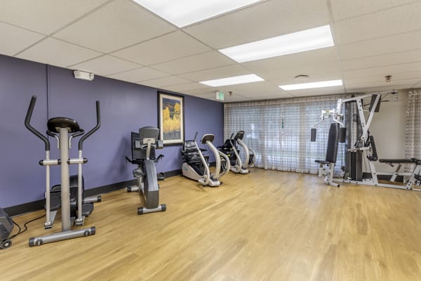 A modern fitness center with exercise equipment lined up on a wooden floor.